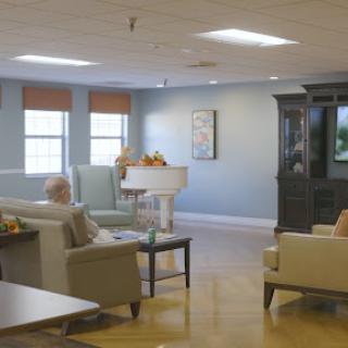 A cozy living room setting in a senior living facility, complete with comfortable seating and a television.