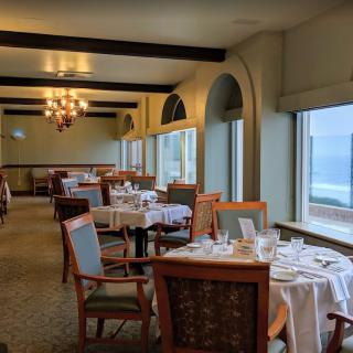 An elegant restaurant dining room with ocean views and neatly set tables.