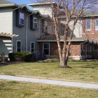 A suburban residential house with a tree and well-kept lawn.
