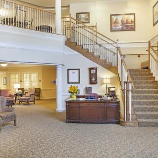 A spacious lobby with a wooden staircase and comfortable seating.