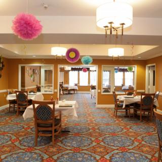 A well-decorated dining room with tables and chairs, featuring colorful hanging decorations and elegant lighting.