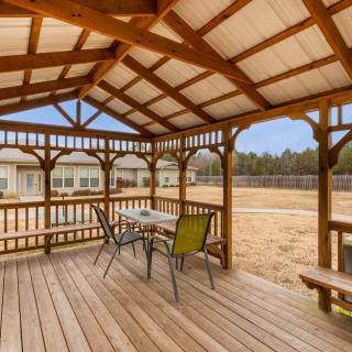A charming wooden gazebo with a table and chairs, overlooking a spacious yard.