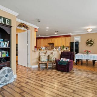 An open-concept living area with a cozy armchair, wooden flooring, and a view into the kitchen.
