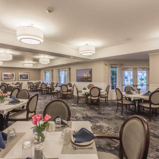 An elegant dining room with neatly arranged tables and chairs, featuring soft lighting and tasteful decor.