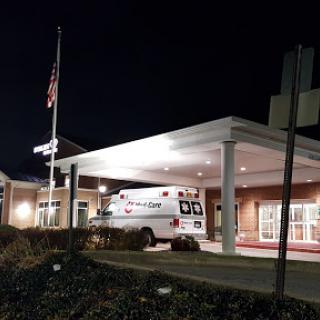 A nighttime view of a hospital entrance with an ambulance parked outside.