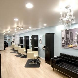 A modern salon interior with sleek design, featuring multiple hair styling stations and luxurious seating.