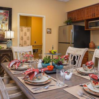 A cozy dining room with a beautifully set table and kitchen in the background.