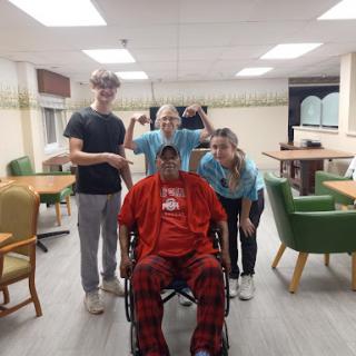 A group of caregivers and a resident enjoy a light-hearted moment in the care facility.