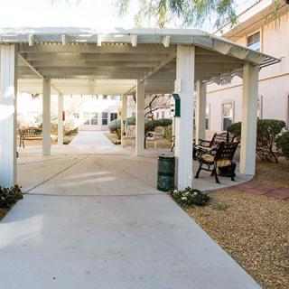 A peaceful outdoor area with a pergola, benches, and a paved walkway.