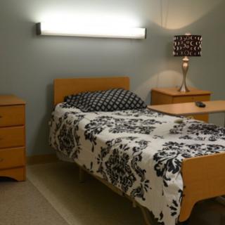A cozy bedroom featuring a neatly made bed with floral bedding and modern furniture.