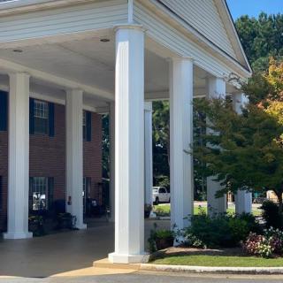 A building entrance with tall columns and surrounding trees.