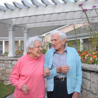 A joyful moment shared between an elderly couple enjoying a stroll in the garden.