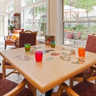 A bright living room with a table set for casual gathering, featuring colorful cups and comfortable seating.
