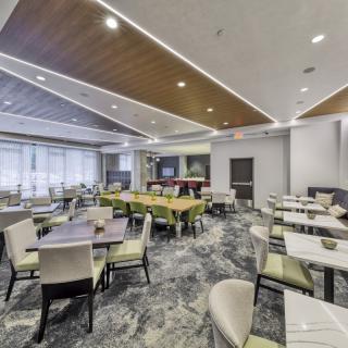 A modern and well-lit dining area with neatly arranged tables and chairs.