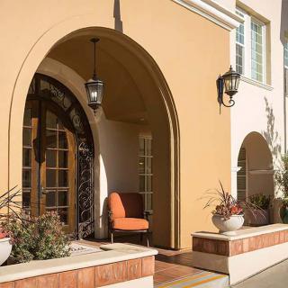 A Mediterranean-style entrance with archways, featuring outdoor seating and decorative lanterns.