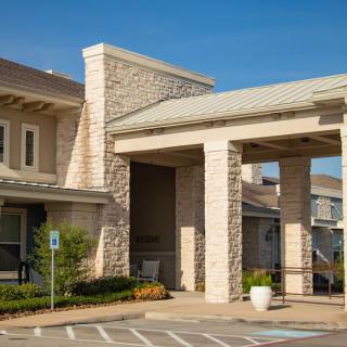 A modern building with a stone exterior and covered entrance, captured in daylight.