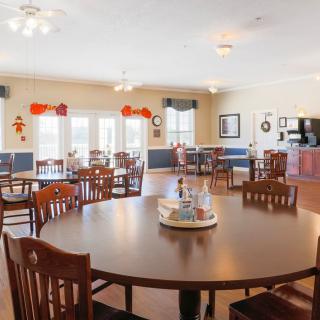 A spacious dining room with several tables and chairs, decorated with festive ornaments.