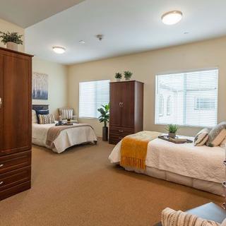 A well-lit bedroom with two beds and wooden furniture.