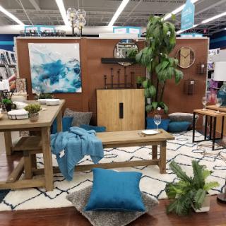 A stylish living room setup featuring a wooden table, vibrant blue accents, and greenery.