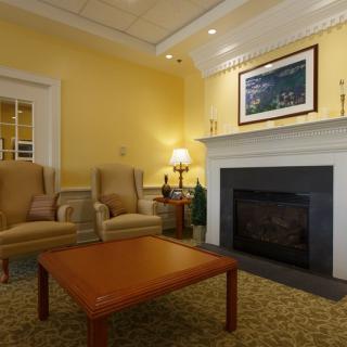 A cozy living room with a fireplace, armchairs, and a wooden coffee table.