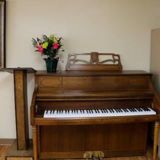 A wooden piano accompanied by a vibrant bouquet of flowers, adding charm to the interior.
