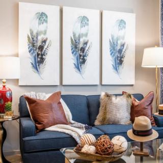 A stylish living room with a blue sofa, decorated with cushions and complemented by artwork and decor.