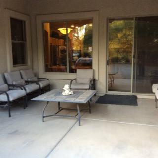 A cozy patio with cushioned seating and a table in front of glass doors.