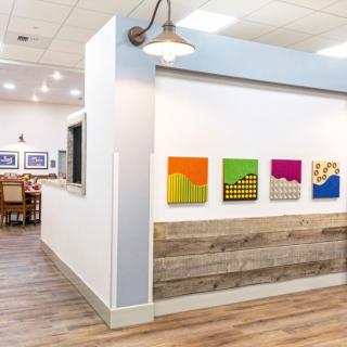 A modern art gallery interior featuring vibrant paintings and wood flooring.