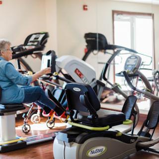 An elderly individual engaging in physical activity on a recumbent bike at a fitness center.