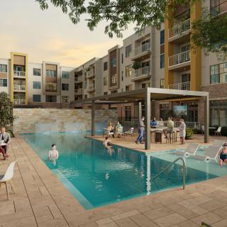 A modern apartment complex with a swimming pool and people relaxing during the evening.