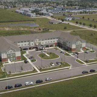 Aerial view of a suburban building complex with surrounding parking area and roads.