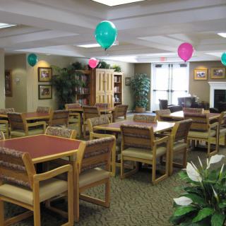 A decorated dining room with tables and chairs, featuring colorful balloons hanging from the ceiling.