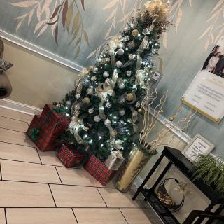 A decorated Christmas tree with wrapped gifts underneath in a warmly lit room.