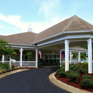 A picturesque residential building with a covered entrance and landscaped driveway.