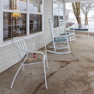 A cozy porch with a rocking chair and metal chairs overlooking a scenic view.