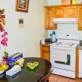 A cozy kitchen with wooden cabinets, a dining table decorated with flowers and fruit, and a classic white oven.