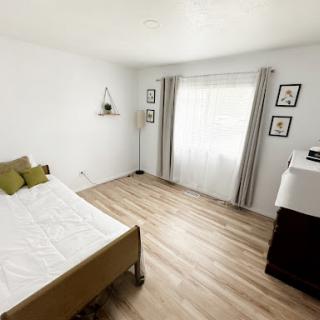 A bright and airy minimalist bedroom with wooden flooring and simple decor.