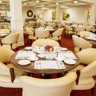 A spacious and elegantly decorated restaurant dining area with neatly arranged tables and comfortable chairs.
