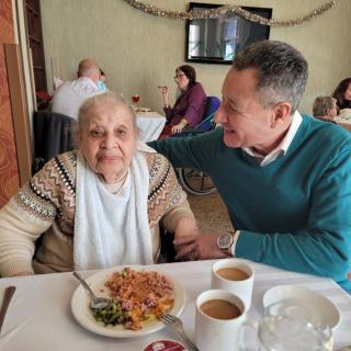 An elderly woman and a man enjoying a meal together in a restaurant setting.