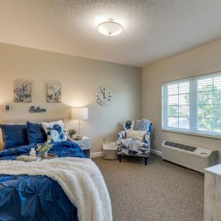 A cozy and well-decorated bedroom with a blue and white color scheme.