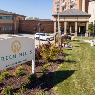 The entrance to a retirement home with a well-maintained garden and a visible sign.