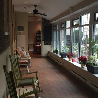A cozy sunroom with rocking chairs and potted plants by large windows.