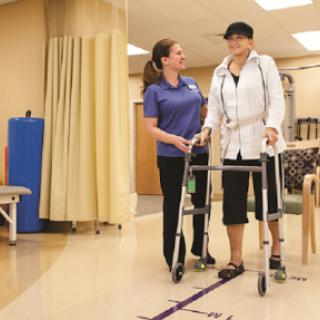 A healthcare professional assists a patient using a walker during a physical therapy session.