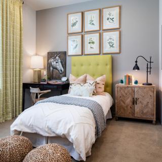A stylishly decorated bedroom with a single bed, colorful headboard, and nature-themed artwork.