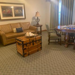 A cozy living room with a leather sofa, wooden chest, round table, and chairs.