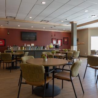 A modern cafe with a spacious seating area, featuring round tables and comfortable chairs.