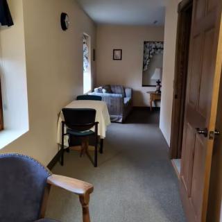 A cozy room with a bed, table, and chairs next to a window.