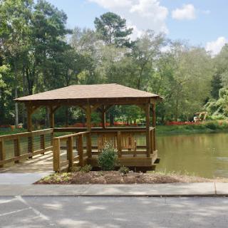 A serene gazebo by the water surrounded by lush greenery.