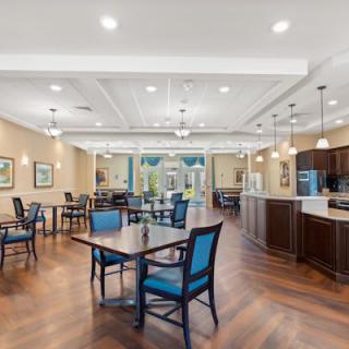 A spacious dining area with tables, chairs, and a view of the kitchen.
