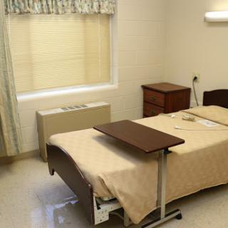 A clean and tidy hospital room with a bed, nightstand, and window.
